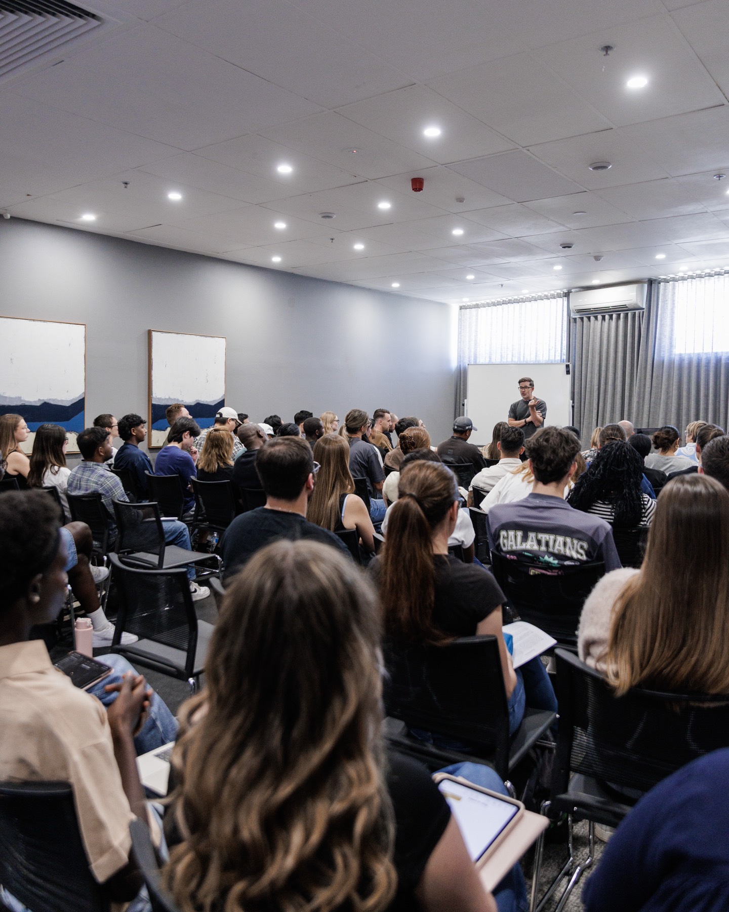 A full room of students listening to a speaker at the front